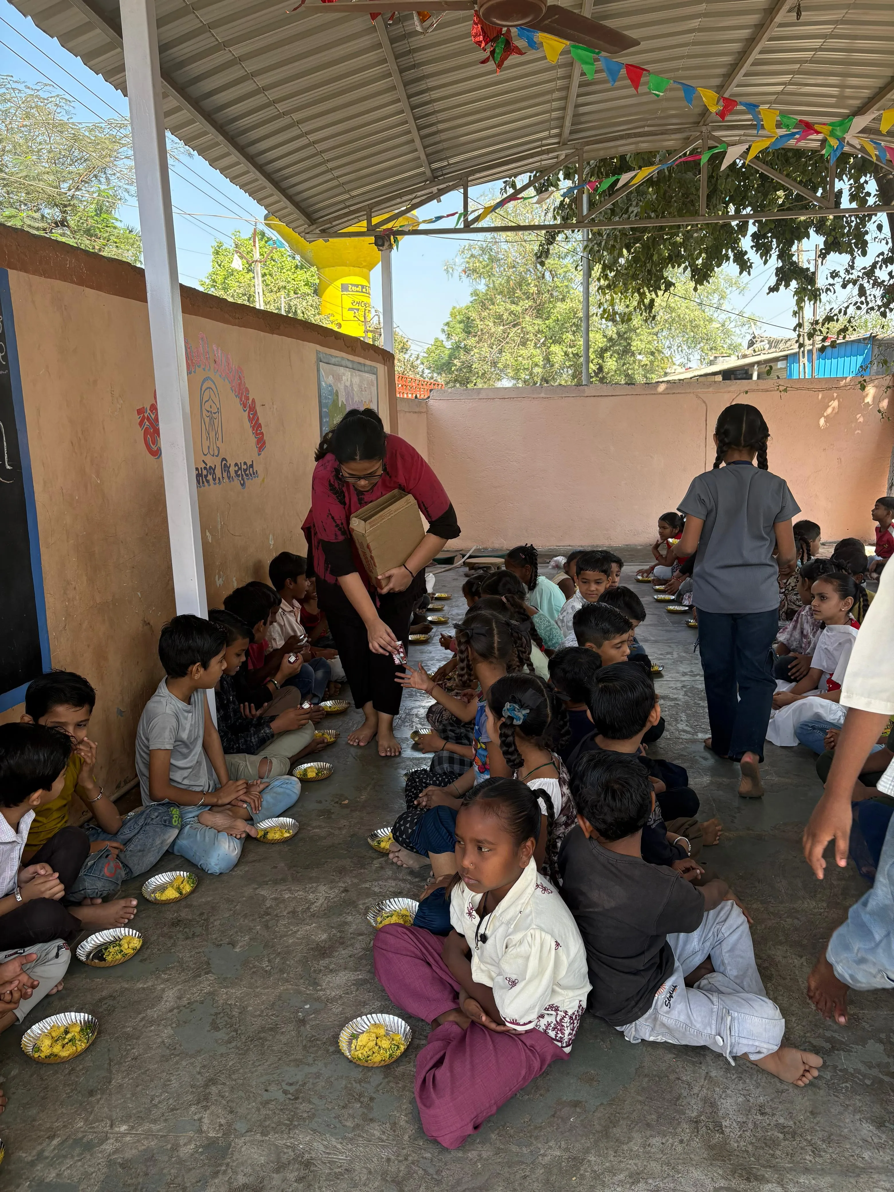 Yash Sharma distributing food to children as part of a community giving initiative.